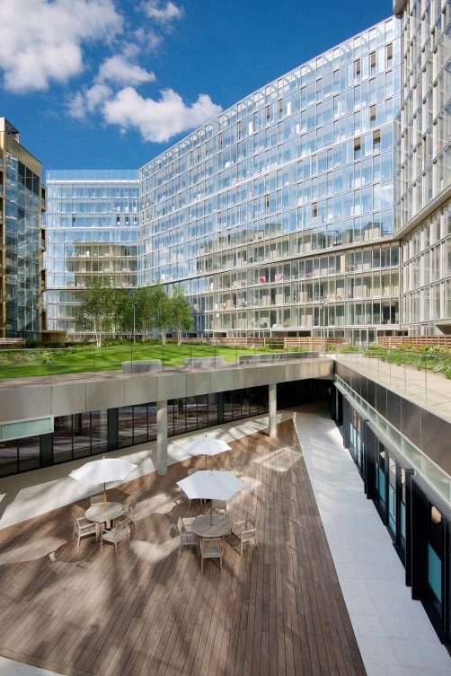 Circus West Village courtyard at Battersea Power Station, with glass-fronted apartment blocks and a landscaped roof terrace