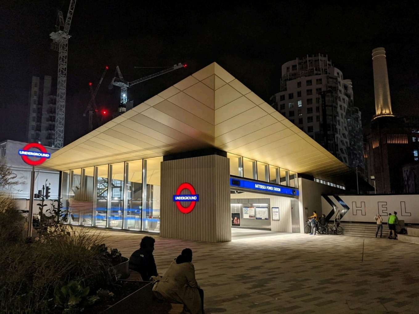 Battersea Power Station Underground station entrance at night, with construction cranes behind