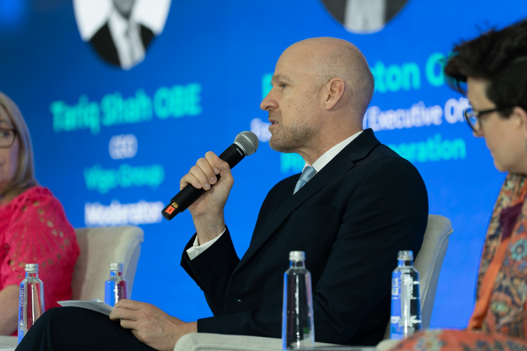 Gordon Adams speaking into a microphone on a conference panel